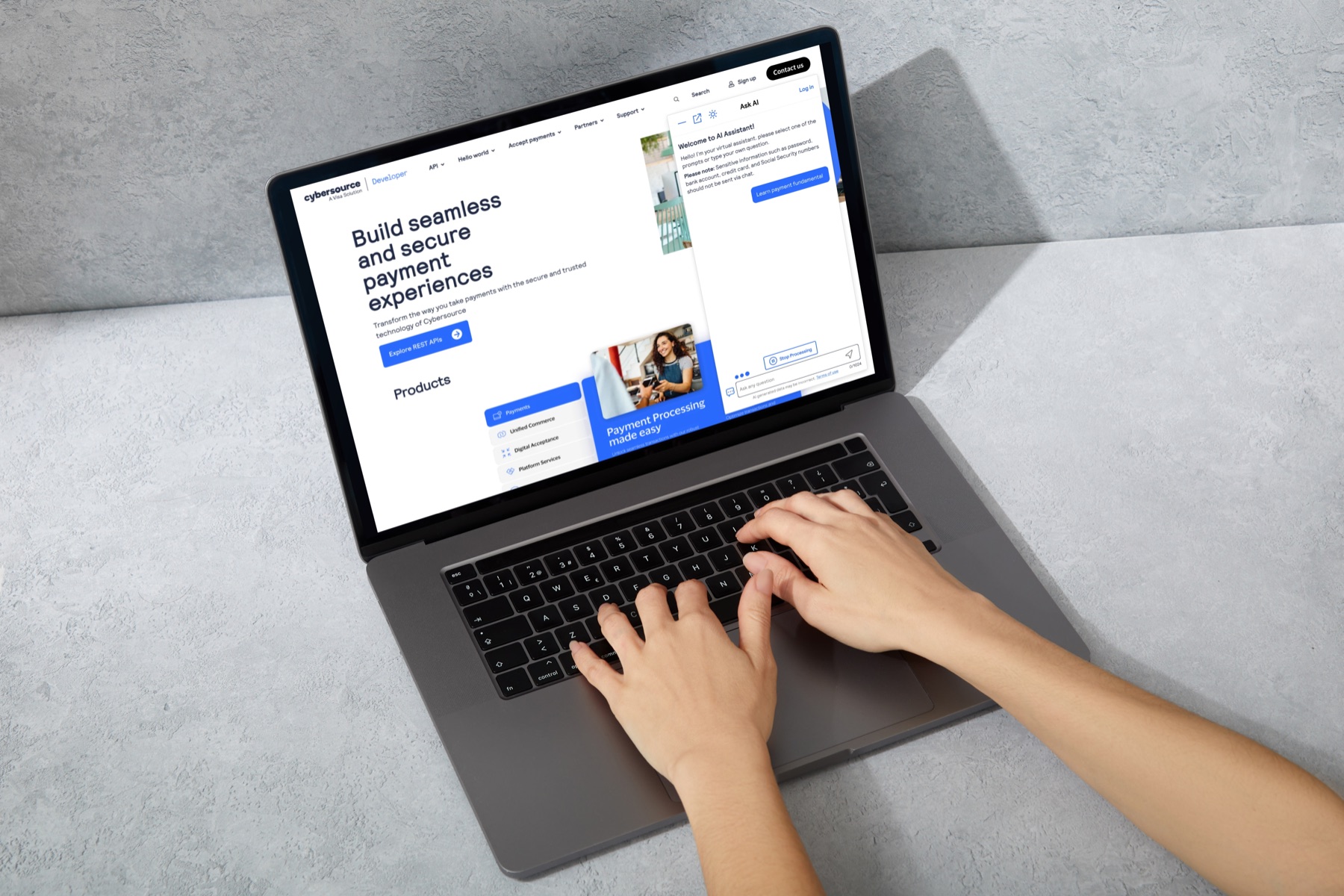 A laptop showing the floating AI assistant docked beside the CyberSource developer portal.
